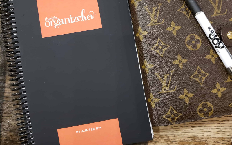 the biz organizeher™ black and rust orange planner cover, next to Louis Vuitton agenda